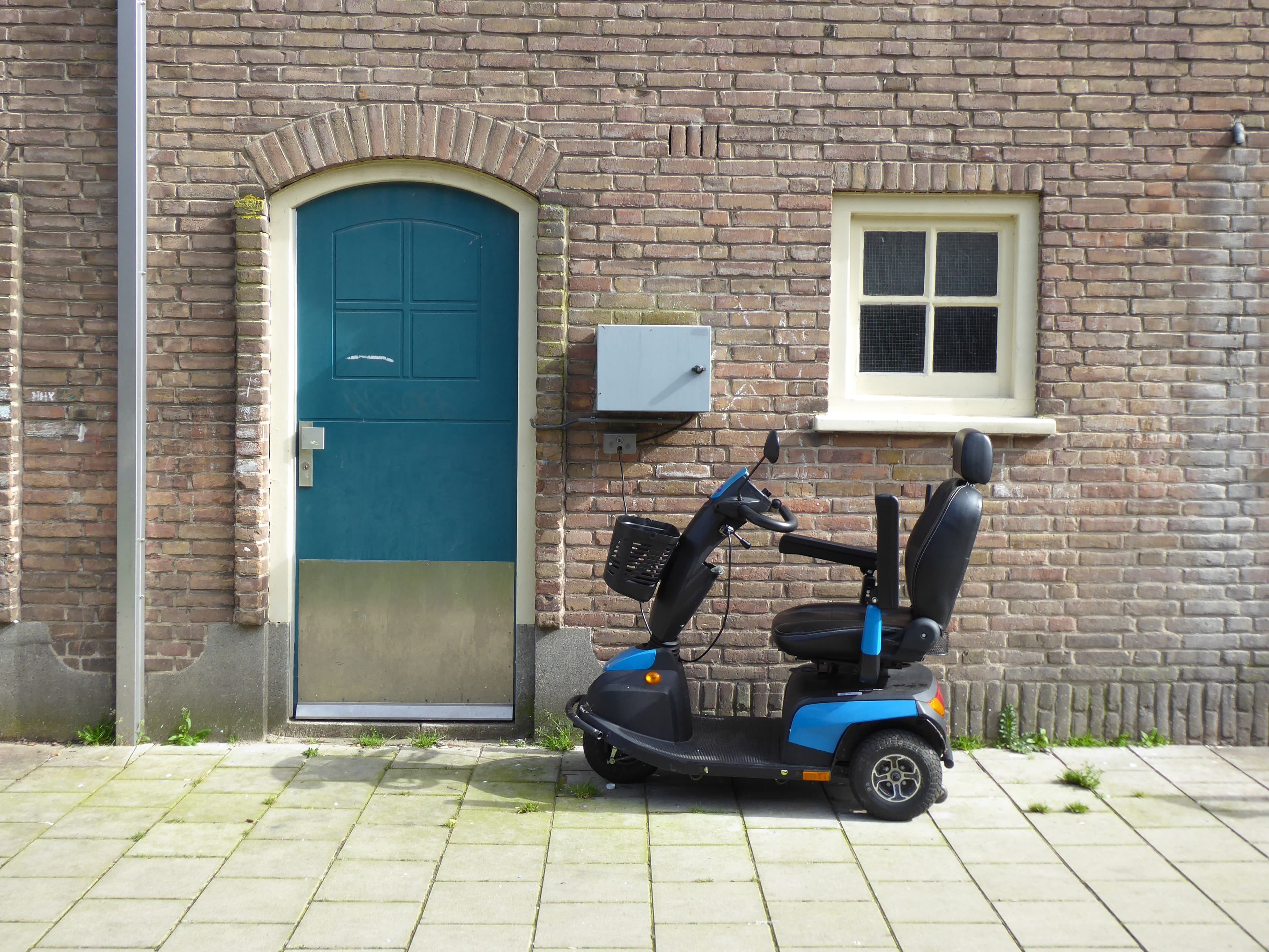 Blue mobility scooter parked outside a brick building