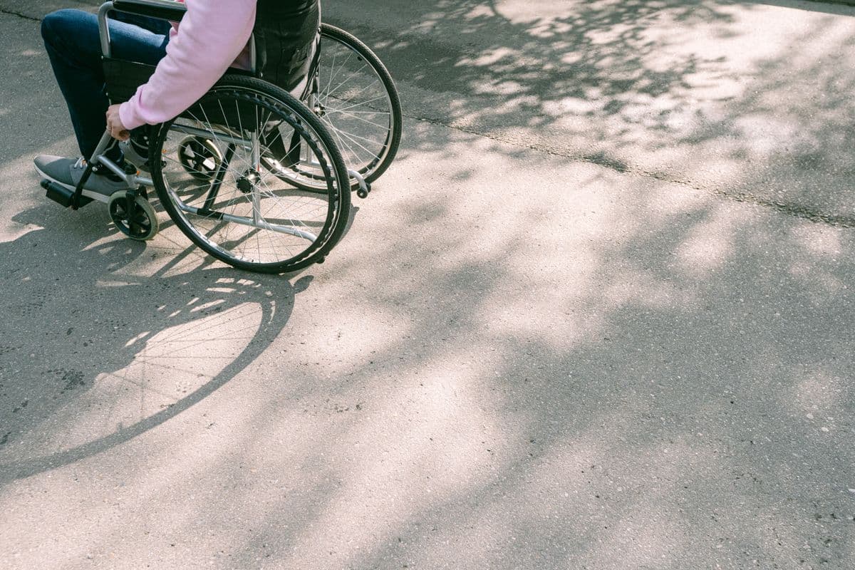 Wheelchair wheel and hand detail outdoors